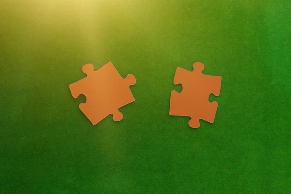 緑の背景に茶色のパズルの2つの部分 論理的な組み合わせ 相互作用 完全な画像の作成 — ストック写真