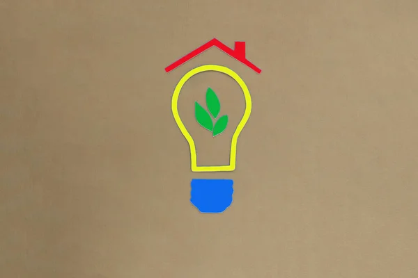 A light bulb, a tree sprout, a red roof on a light brown background. Estate investment. business project.