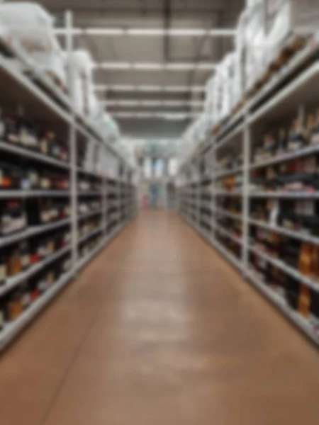 Blurred background of a row of shelves with goods inside the supermarket. Corridor of shelves with products sold in the store.