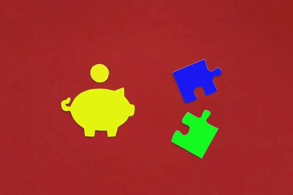 Piggy Bank for money, puzzles in blue and green on a red background. Budget planning, accumulation of financial funds.
