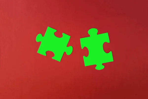 パズルの2つの部分は赤の背景に緑色です 団結と接触という概念です — ストック写真