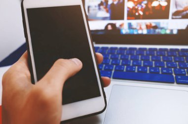 Cep telefonu ile boş siyah perde ofiste tutan adam.