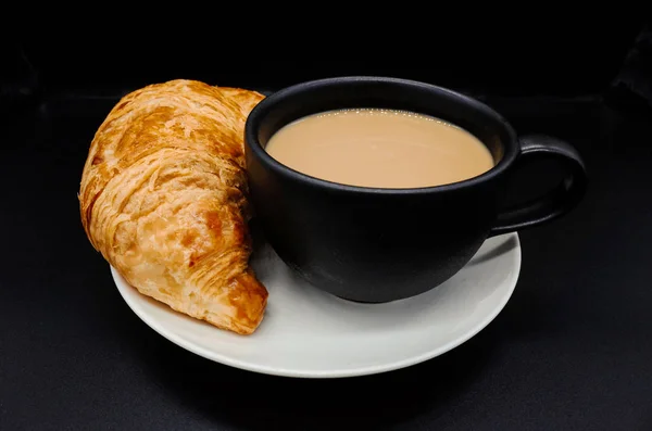 Cup of coffee and croissants on black backgroun