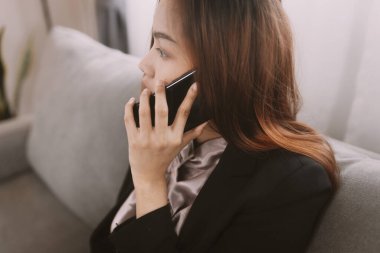 Defterde çalışan bir kadın alternatif ofis için ev konseptinde kanepeye oturur..