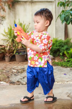 Oynayacağın zaman, sert oyna! Yazlık şort giyen, ayakta duran, ateş eden, Songkran Günü 'nde oynamak için bekleyen zeki çocuk.. 
