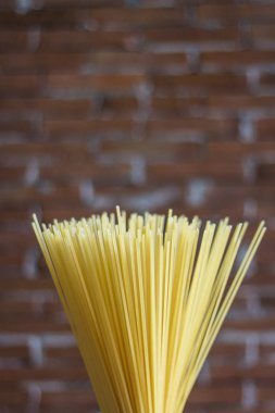 Rustik bir arka plan üzerinde sarı uzun spagetti. Sarı İtalyan makarnası. Uzun spagetti. Ham spagetti bolonez. Çiğ spagetti. Gıda arka plan konsepti. İtalyan yemekleri ve menü konsepti.