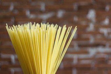 Rustik bir arka plan üzerinde sarı uzun spagetti. Sarı İtalyan makarnası. Uzun spagetti. Ham spagetti bolonez. Çiğ spagetti. Gıda arka plan konsepti. İtalyan yemekleri ve menü konsepti.