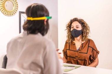 Güzellik Salonu, koronavirüs salgınından sonra güvenlik önlemleriyle yeniden açılıyor. Güzellik salonunda maske takan bir müşteri açıklamalara özen gösterir. Covid 19