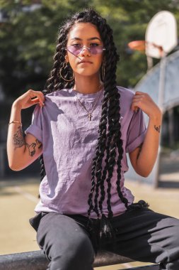 Mor gömlekli, uzun örgülü, koyu tenli genç bir kadının baştan çıkarıcı görünüşü.