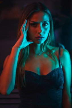 Mavi ve kırmızı ışıkla aydınlatılmış güneş gözlüklü esmer beyaz kız portresi. Gece şehir fotoğrafçılığı