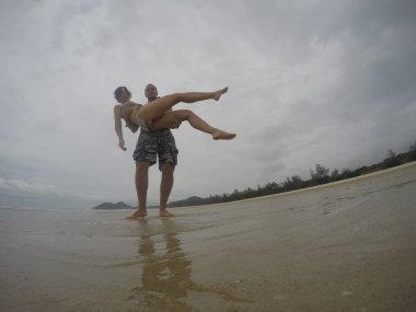 Mutlu aşk çifti denizde eğleniyor ve poz veriyor, Bai Tu Long Bay, Vietnam. 