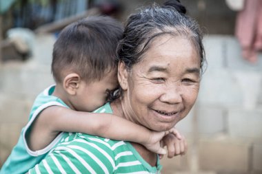Luang Prabang, Laos - Ağustos 2017: Luang Prabang 'ın yanındaki kırsal bir kasabada torunuyla birlikte bir büyükanne