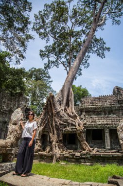 Angkor, Kamboçya 'daki Budist tapınaklarının yıkıntılarının yanında duran genç bir kadın.