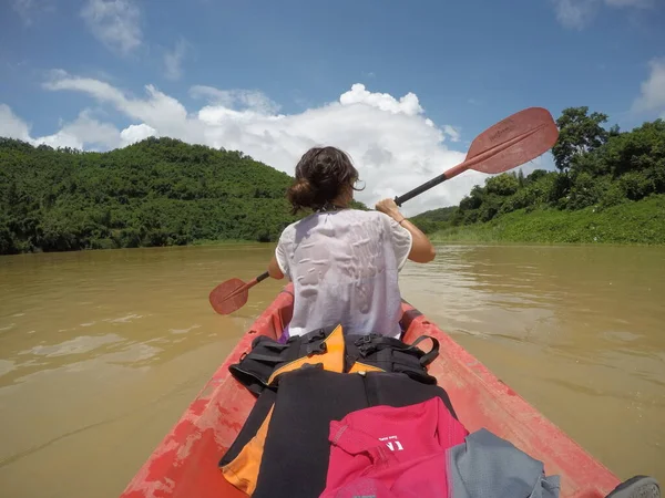 a woman is kayaking in the river, back view