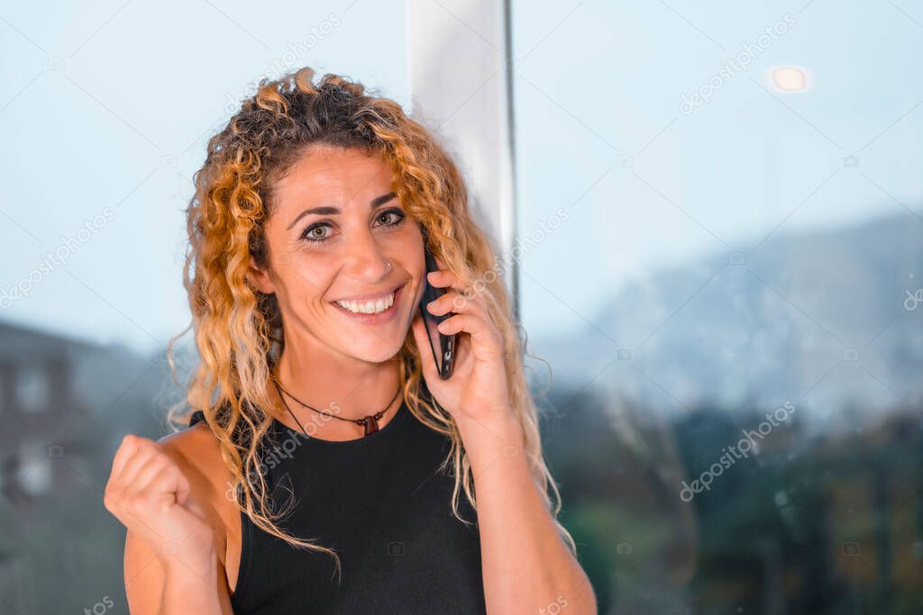 Session young entrepreneurs in the office,  young blonde Caucasian woman with curly hair talking on the phone in the office