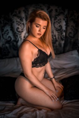 çekici genç kadın yatakta poz veriyor.