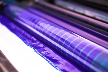 Geleneksel ofset baskı. Mürekkeple CMYK, Cyan, morumsu, sarı ve siyah. Grafik sanatı, ofset baskı. Dört küme mavi mürekkepli uzaklık makinesindeki yazıcı silindirinin ayrıntıları