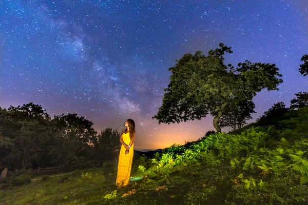 woman in yellow dress posing against starry sky