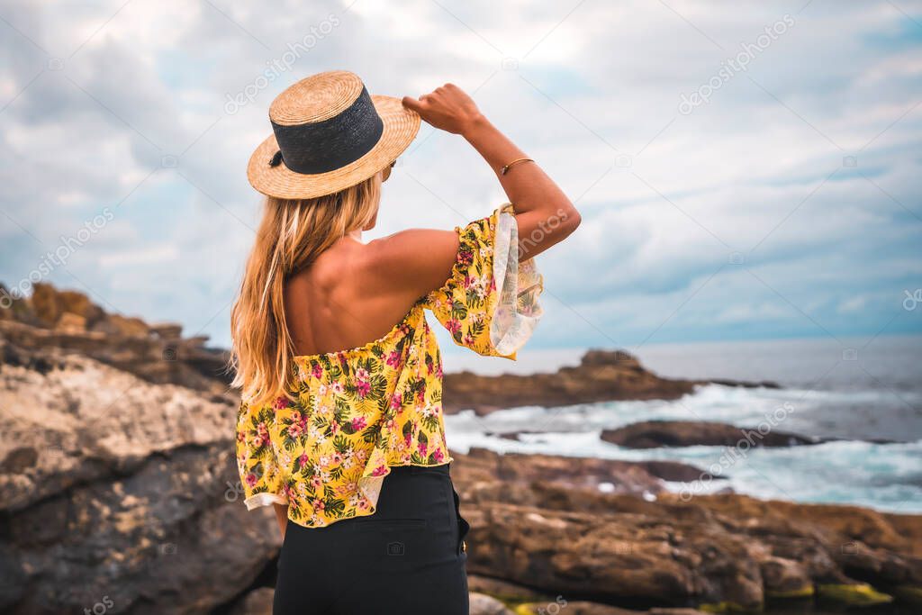 Blonde beautiful woman at rocky coast