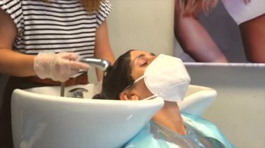 Kuaför ve müşteri maske takıyor. Covid-19 salgınında kuaförlerin güvenlik önlemleriyle yeniden açılacak. Yeni normal, koronavirüs, sosyal uzaklık