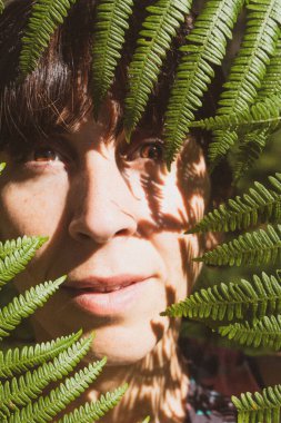 Eğreltiotu yaprakları arasında kadın yüzü