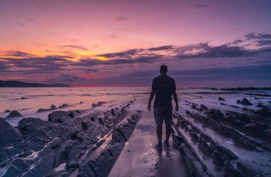 Sakoneta Sahili 'nde genç bir adam ve güzel Flysch' i Deba kasabasında, Bask Sahili 'nin batı ucunda, Guipzcoa' da. Bask Ülkesi