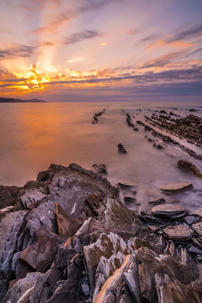 Stones at sunset of the Geopark called Flysch on the beach of Sakoneta in the town of Deba, at the western end of the Geopark of the Basque Coast, Guipzcoa. Basque Country. Vertical photo