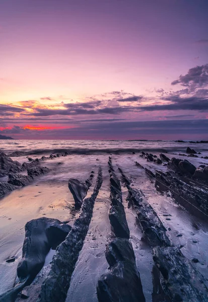 Purple sunset on the Sakoneta beach and its beautiful Flysch in the town of Deba, At the western end of the Basque Coast Geopark, Guipzcoa. Basque Country