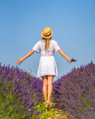 Kırsal yaşam tarzı, beyaz elbiseli ve lavanta tarlasında mor çiçeğiyle saman şapkalı beyaz bir kadın. Navarra, İspanya. Sırtın çiçeklerin arasındayken