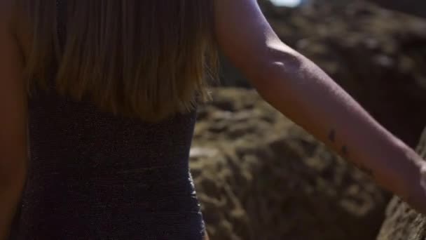 在坎塔布里亚海岸的一个海湾里 住着一个漂亮的年轻的高加索黑发姑娘 穿着黑色泳衣 享受夏天和夏天的生活方式 在岩石之间行走 — 图库视频影像