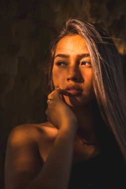 Yüzünde hafif bir ışıkla bir ağaca yaslanmış genç bir Latin esmer. Tatlı ve şehvetli bir portre.