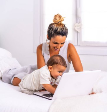 Beyaz bir anne, oğlu ile birlikte yatağın üstündeki odada. Ailesiyle video görüşmesinde bir yıldan az içmiş. Covid-19 salgınında büyükanne ve büyükbabayla iletişim.