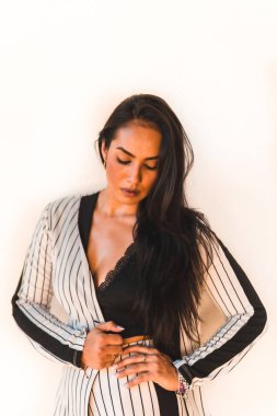 Yaşam tarzı, düz saçlı, beyaz takım elbiseli, siyah çizgili esmer kız. Beyaz arka plan. Cinsel açıdan farklı, farklı görünümlü, moda editörü.