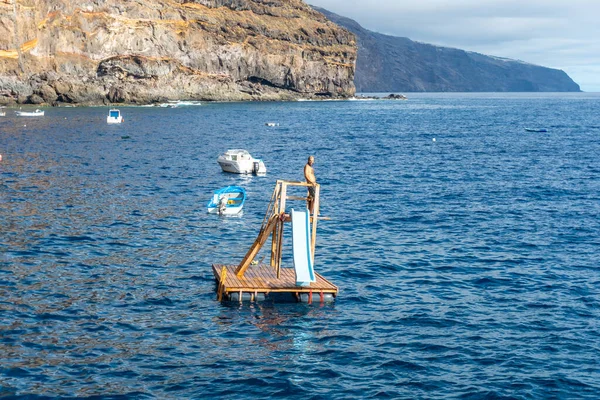 A young man jumping into the sea water in the cove of Puerto de Puntagorda, La Palma island, Canary Islands. Spain