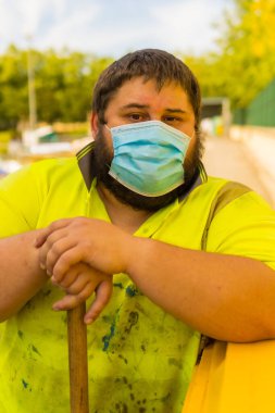 Geri dönüşüm fabrikasındaki işçiler ya da temiz nokta ve yüz maskeli çöpler ve güvenlik korumalarıyla yeni normal, koronavirüs salgını, covid-19. Sarı plastik bir kapta portre