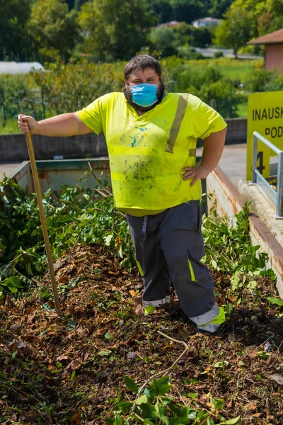 Worker in a recycling factory or clean point and garbage with a face mask and with security protections, new normal, coronavirus pandemic, covid-19. Portrait in the container of the bad herb