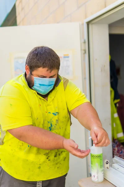 Worker in a recycling factory or clean point and garbage with a face mask and plastic protective screen, new normal, coronavirus pandemic, covid-19. Cleaning your hands with disinfectant liquid