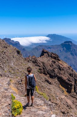 Caldera de Taburiente, La Palma, Kanarya Adaları 'nın tepesinde Roque de los Muchachos yolunda yürüyen genç bir kadın. İspanya
