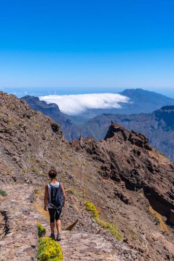 Caldera de Taburiente, La Palma, Kanarya Adaları 'nın tepesinde Roque de los Muchachos yolunda yürüyen genç bir kadın. İspanya