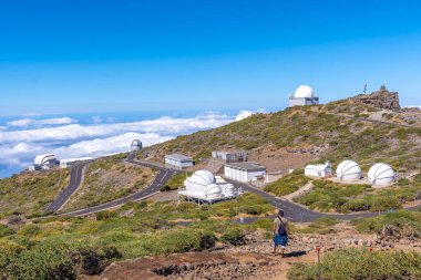 A young man on the trail looking at the telescopes of the Roque de los Muchachos national park on top of the Caldera de Taburiente, La Palma, Canary Islands. Spain clipart