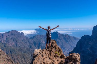Caldera de Taburiente 'nin tepesinde genç bir kadın Roque de los Muchachos yakınlarında bir yaz öğleden sonra kollarını açmış, La Palma, Kanarya Adaları' nda. İspanya