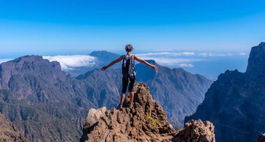 Caldera de Taburiente 'nin tepesinde genç bir kadın Roque de los Muchachos yakınlarında bir yaz öğleden sonra kollarını açmış, La Palma, Kanarya Adaları' nda. İspanya