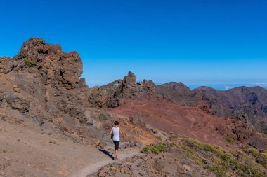 Bir yaz öğleden sonra Roque de los Muchachos yakınlarındaki Caldera de Taburiente volkanı üzerinde yürüyen genç bir kadın, La Palma, Kanarya Adaları. İspanya