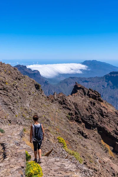 Caldera de Taburiente, La Palma, Kanarya Adaları 'nın tepesinde Roque de los Muchachos yolunda yürüyen genç bir kadın. İspanya