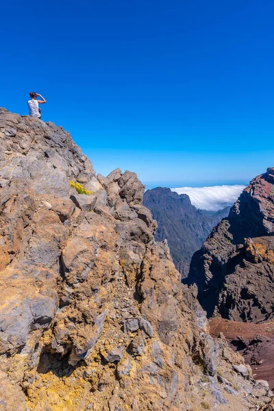 Genç bir kadın dinleniyor ve Kanarya Adaları 'ndaki Caldera de Taburiente tepesindeki Roque de los Muchachos Ulusal Parkı' na bakıyor. İspanya