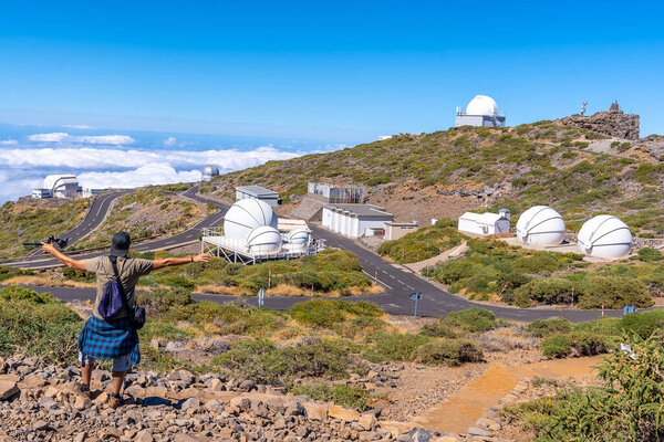 A young man on the trail looking at the telescopes of the Roque de los Muchachos national park on top of the Caldera de Taburiente, La Palma, Canary Islands. Spain