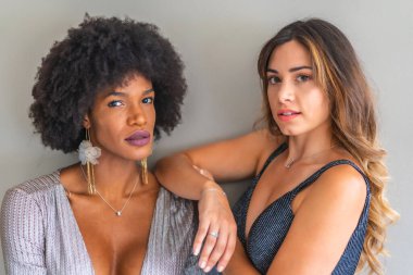 Balo elbiseli iki çok ırklı arkadaş özel partiye gitmek için gece dışarı çıkmaya hazırlar. Gri ve mavi gece elbiseleri, sarışın beyaz kız, siyah saçlı kız.