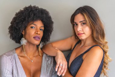 Balo elbiseli iki çok ırklı arkadaş özel partiye gitmek için gece dışarı çıkmaya hazırlar. Gri ve mavi gece elbiseleri, sarışın beyaz kız, siyah saçlı kız.