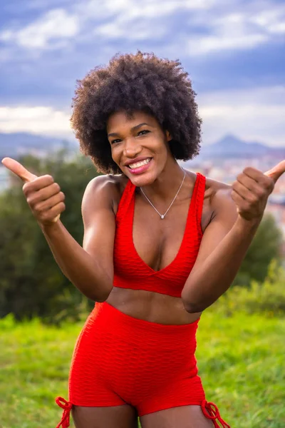 Fitness with a young black girl with afro hair, doing exercises with great joy, exercising in the field, gray sport suit, fit girl, healthy life, copy paste space