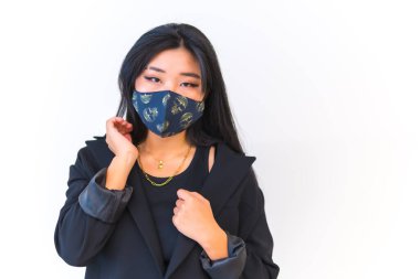 Siyah ceketli genç Asyalı kız beyaz arka planda yüz maskesi takıyor, yeni normal, sosyal mesafe. Çin 'in Wuhan şehrinde doğan kız, Coronavirus, covid-19